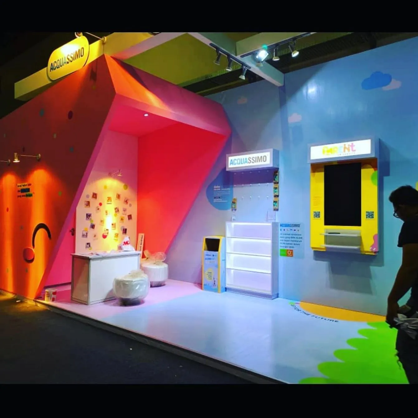 Detail booth ACQUASSIMO dengan dinding warna-warni dan rak produk